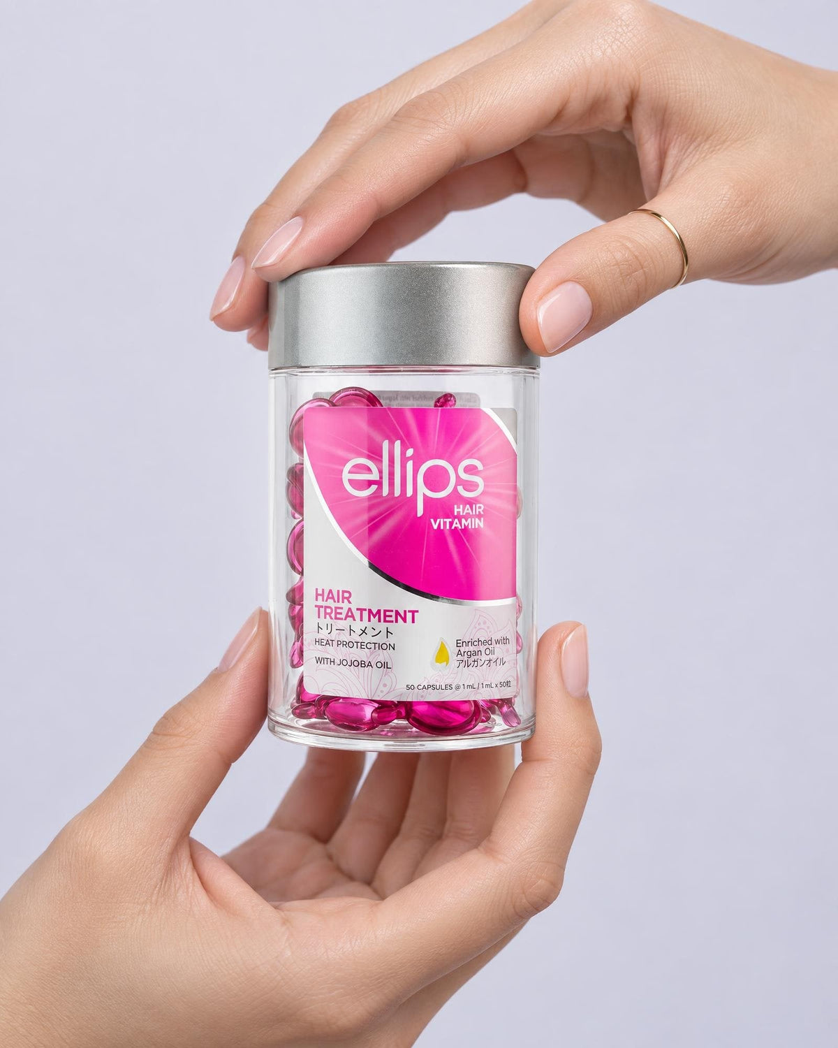 Två händer som håller en burk Ellips Hair Treatment