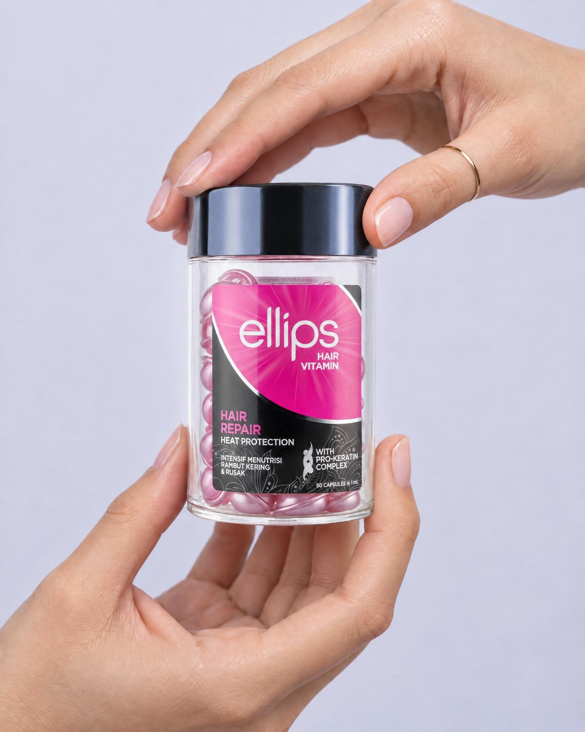 Två händer som håller en burk Ellips Hair Repair