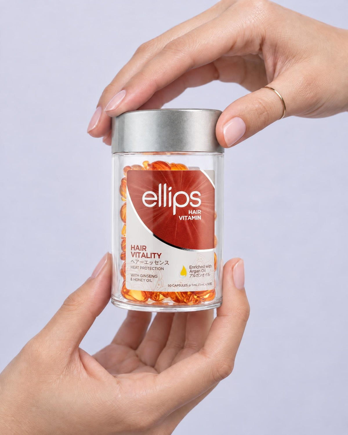 Två händer som håller en burk Ellips Hair Vitality